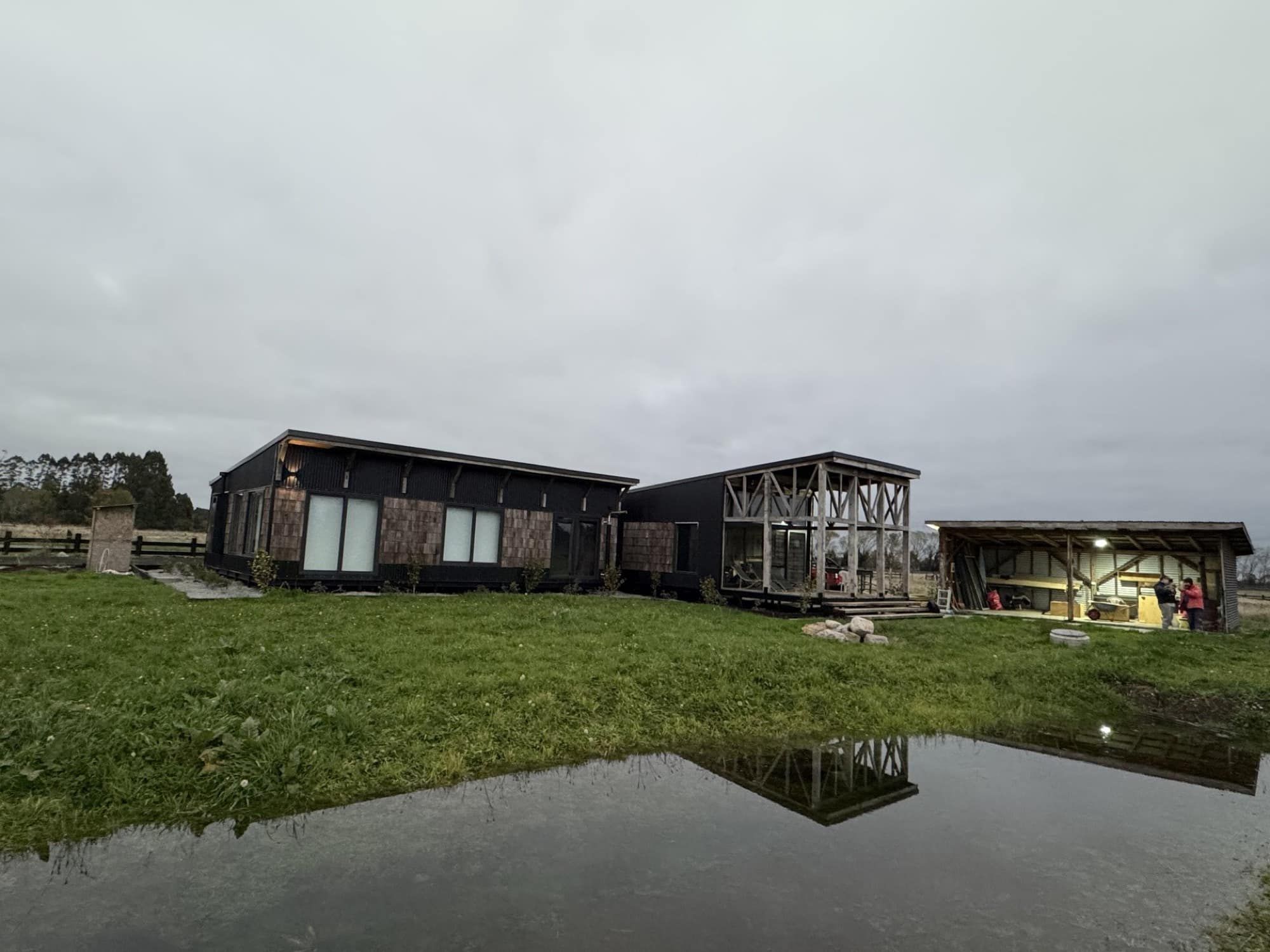 Casa Fundo Volcanes: volúmenes de madera oscura y tejuela en la pradera